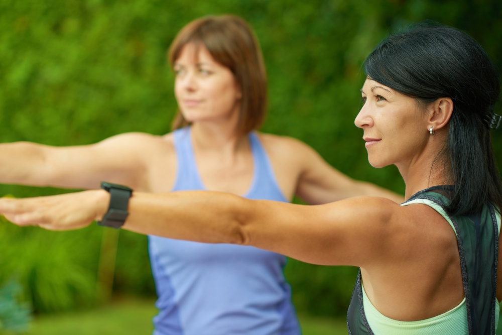 Two mature women keeping fit by doing yoga in the summer.jpeg